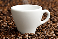 Hot cup of coffee on a bed of coffee beans Hot cup of coffee on a bed of coffee beans